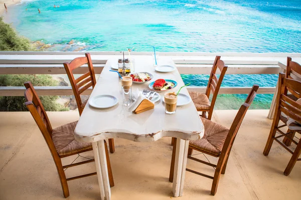 Almuerzo tradicional con deliciosa ensalada griega fresca, frappe y brusketa servido para el almuerzo en el restaurante al aire libre con hermosa vista al mar y al puerto —  Fotos de Stock