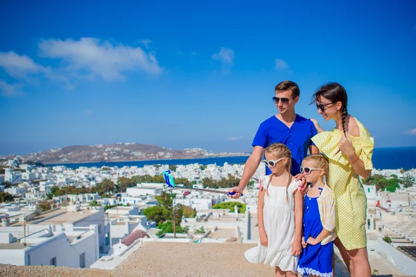 Familjesemester i Europa. Föräldrar och barn att ta selfie foto bakgrund Mykonos stad i Grekland — Stockfoto