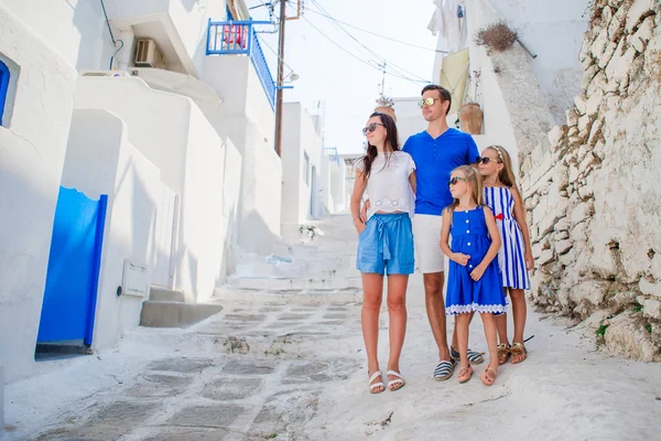 Familj vacayion i Europa. Föräldrar och barn på gatan i typiska grekiska traditionella byn med vita väggar och färgglada dörrar på Mykonos Island, i Grekland — Stockfoto