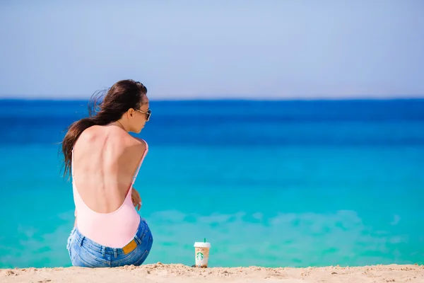 Joven mujer hermosa con café en la playa durante las vacaciones tropicales. Chica disfrutar de su wekeend en una de las hermosas playas de Mykonos, Grecia, Europa . — Foto de Stock