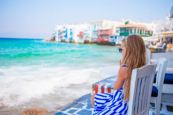 Rozkošná holčička v Malé Benátky nejoblíbenější turistická oblast na ostrově Mykonos, Řecko. Krásné dítě úsměv a podívejte se do kamery na Malé Benátky pozadí. — Stock fotografie