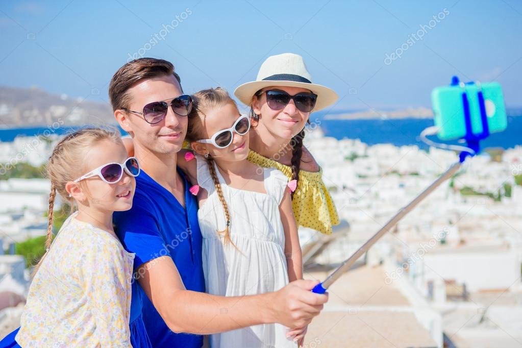 Family vacation in Europe. Parents and kids taking selfie photo background Mykonos town in Greece