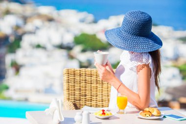 Mikonos kentine muhteşem manzaralı açık kafede kahvaltı güzel zarif bayan. Resort Restoran deniz manzaralı lüks otel terasında sıcak kahve içme kadın.