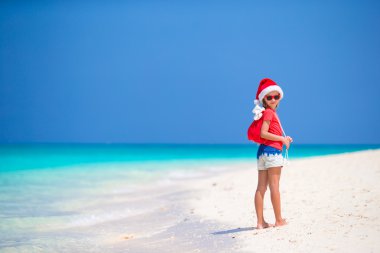 Sevimli küçük kız Santa şapka ve hediyeler Noel beach tatil sırasında bir çanta
