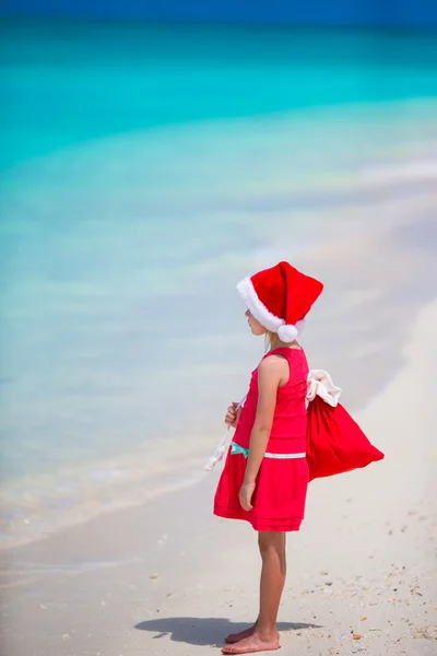 Entzückendes kleines Mädchen mit Weihnachtsmütze im Weihnachtsurlaub am Strand — Stockfoto