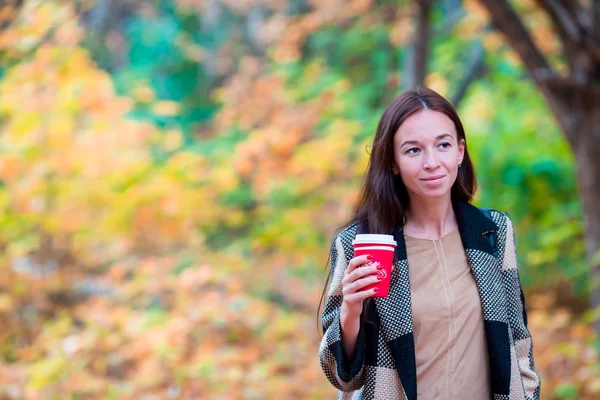 美丽的女人喝咖啡在秋天公园下秋天的落叶。咖啡要走 — 图库照片