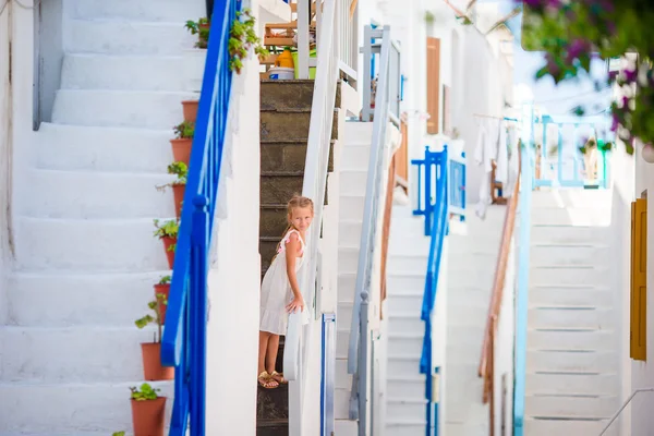 Schattig meisje in blauwe jurk op straat van typische Griekse traditionele dorp met verbazingwekkende stappen, witte wanden en kleurrijke deuren op het eiland Mykonos, in Griekenland — Stockfoto