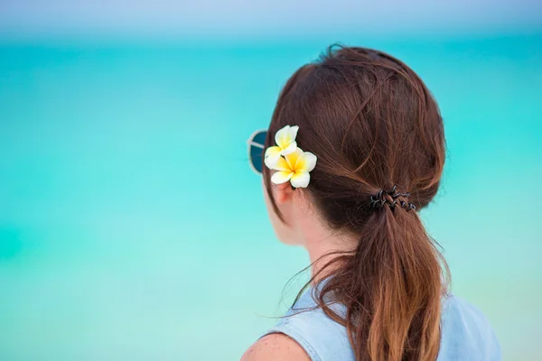 Giovane bella donna durante le vacanze al mare tropicale. Godetevi una vacanza suumer da sola sulla spiaggia con i fiori frangipani tra i capelli — Foto Stock