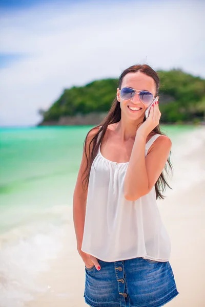 Joven hermosa mujer en la playa hablando por su teléfono inteligente — Foto de Stock