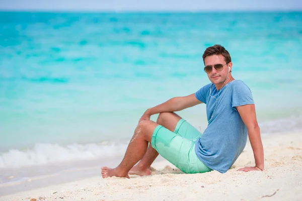 Feliz joven disfrutando de la música en la playa de arena blanca — Foto de Stock