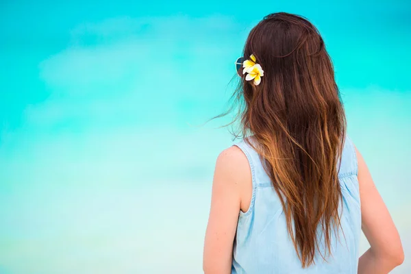 Junge schöne Frau während eines tropischen Strandurlaubs. Genießen Sie den suumer Urlaub allein am Strand mit Frangipani-Blumen im Haar — Stockfoto