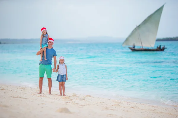 Młody ojciec i małe dziewczynki w Santa hat na plaży — Zdjęcie stockowe