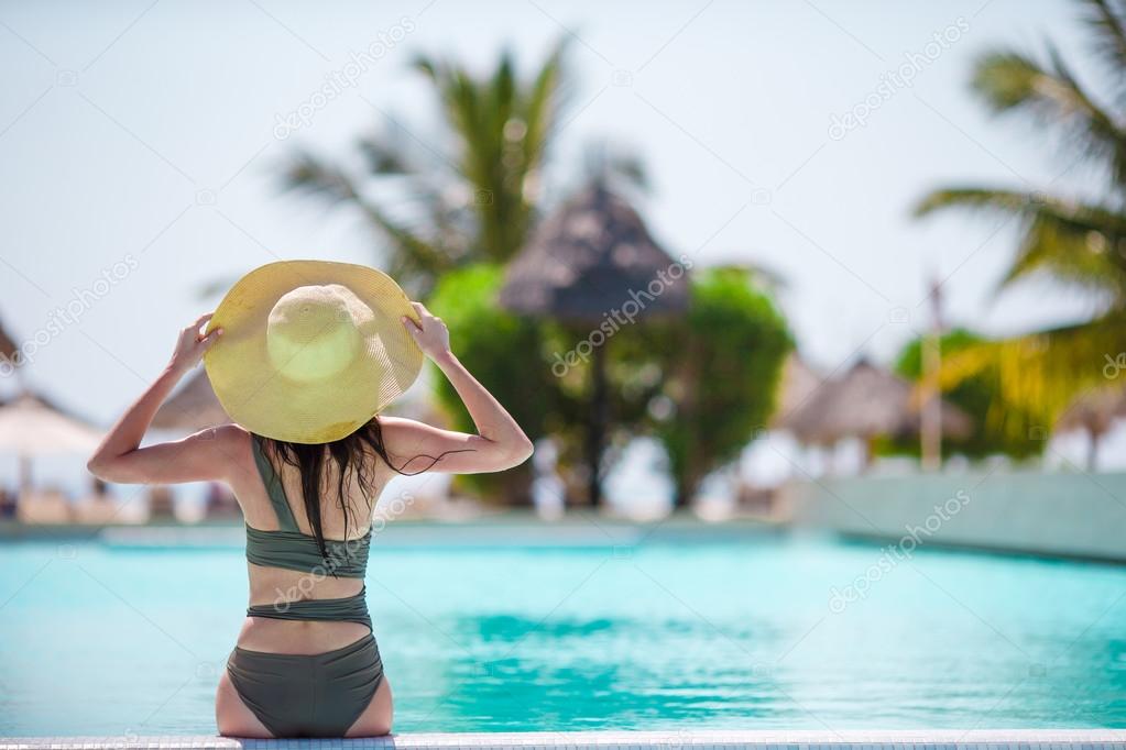 Beautiful young woman relaxing in pool at luxury hotel