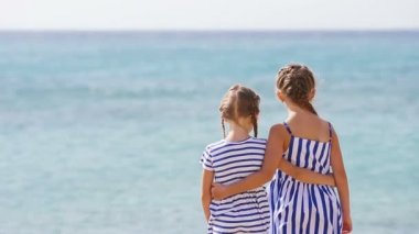 Plaj tatili sırasında birlikte sevimli küçük kızlar. Çocuklar Yunan plajında yaz tatilinin tadını çıkarıyor