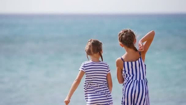 Adorables niñas juntas tiran piedras durante las vacaciones en la playa. Los niños disfrutan de las vacaciones de verano en la playa griega — Vídeos de Stock