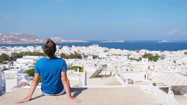 Mladý chlapec na ulici s úžasným výhledem na Mykonos, Řecko. Krásné známé pozadí — Stock video