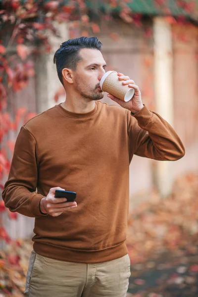 Junger Mann trinkt Kaffee im Herbstpark — Stockfoto