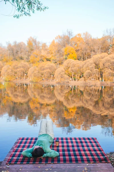 Herbstkonzept - schöne Frau trinkt Kaffee im Herbstpark unter Herbstlaub — Stockfoto