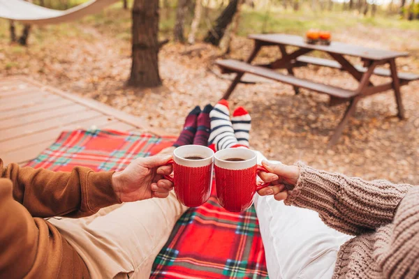 Hot cups of tea in hands in woollen sweater on background of cozy house — Stock Photo, Image