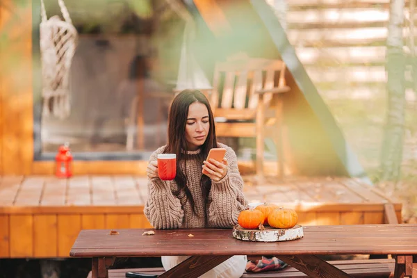 Fröhliche junge Frau beim Kaffeetrinken am Holztisch im Freien — Stockfoto