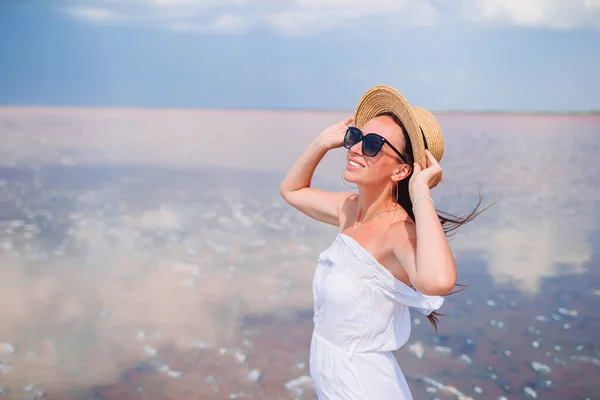 Žena v klobouku chodit na růžové slané jezero za slunečného letního dne. — Stock fotografie