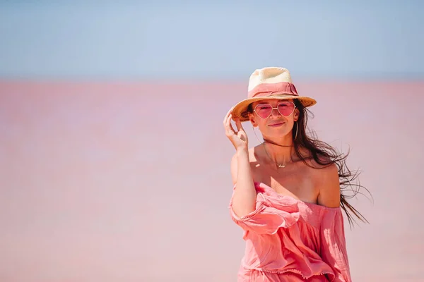 Mujer en sombrero caminar en un lago de sal rosa en un día soleado de verano. —  Fotos de Stock