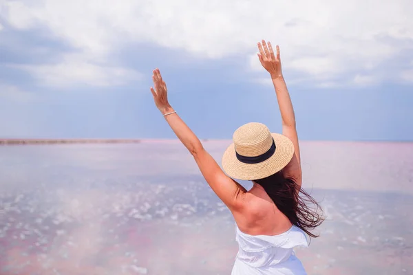 Vrouw in muts lopen op een roze zoutmeer op een zonnige zomerdag. — Stockfoto