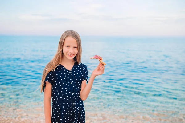 Glückliches Mädchen, das Spaß am Strand hat und Pizza isst — Stockfoto