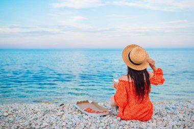 Kadın plajda pizzayla piknik yapıyor.