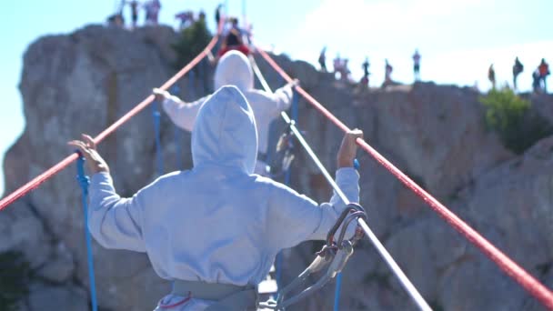 Girls crossing the chasm on the rope bridge. Black sea background, Crimea — Stock Video