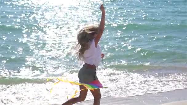 सूर्यास्ताला समुद्रकिनारावर एक किट उड्डाण करणारी लहान मुलगी — स्टॉक व्हिडिओ