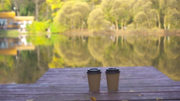 Coffee to go on a wooden pier at the lake on an autumn day — Stock Video