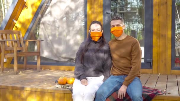 Familia de dos en máscaras en la terraza en otoño — Vídeos de Stock