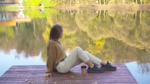 Sonbahar konsepti. Güz parkında göl kenarında güzel bir kız. — Stok video