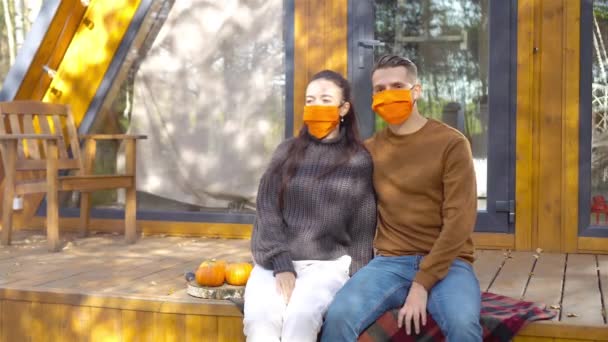 Familia de dos en máscaras en la terraza en otoño — Vídeos de Stock