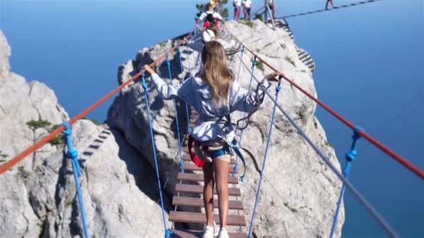 Chicas cruzando el abismo en el puente de cuerda. El fondo negro de mar, la Crimea — Vídeo de stock