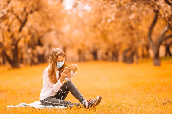 Niña usando máscara médica protectora al aire libre en el parque —  Fotos de Stock