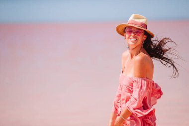 Güneşli bir yaz gününde pembe tuz gölünde yürüyen şapkalı bir kadın..