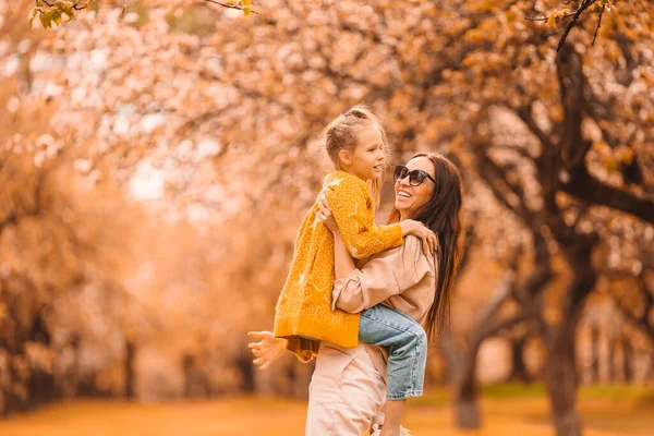 Little girl with mom outdoors in park at autumn day — Stock Photo, Image