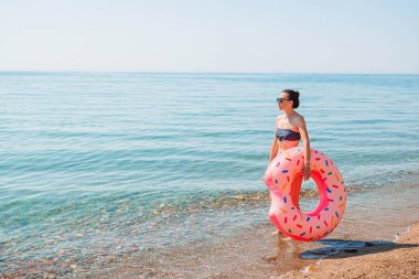Plajda beyazlar içindeki genç kadın.