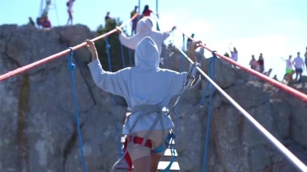 Chicas cruzando el abismo en el puente de cuerda. El fondo negro de mar, la Crimea — Vídeos de Stock
