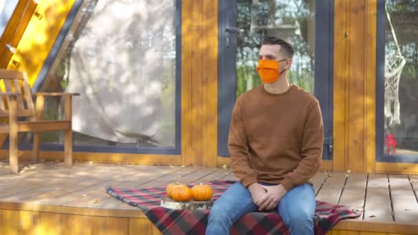 Hombre con máscara en la terraza en otoño — Vídeos de Stock