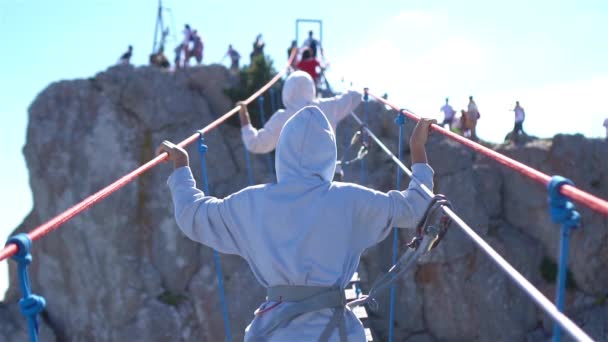 Girls crossing the chasm on the rope bridge. Black sea background, Crimea — Stock Video