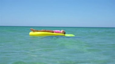 Denizdeki şişme şiltenin üzerinde sevimli bir kız.