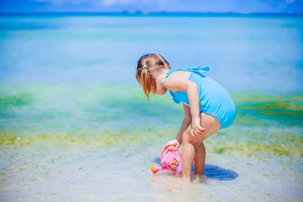Adorable niña jugando con juguetes de playa en la playa tropial blanca —  Fotos de Stock