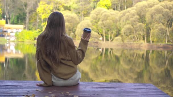 Podzimní koncept - krásná dívka v podzimním parku na jezeře — Stock video