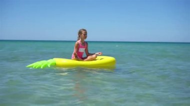 Denizdeki şişme şiltenin üzerinde sevimli bir kız.