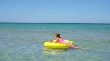 Denizdeki şişme şiltenin üzerinde sevimli bir kız.