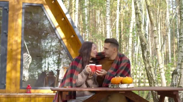 Молода пара з кавою на подвір'ї свого будинку восени — стокове відео