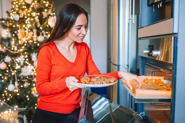 Mujer joven en sombrero de Navidad hornear pan de jengibre en casa. —  Fotos de Stock